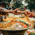 Colorful street food scene in India with vendor serving traditional snacks at a busy market.