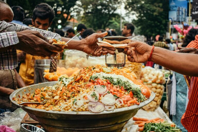 Colorful street food scene in India with vendor serving traditional snacks at a busy market.