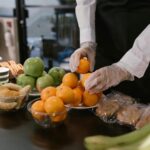 Caterer arranging fresh fruits and snacks on a table for a food service event.